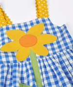 Frugi 100% organic cotton dress in blue and white gingham laid flat showing  a large sunflower patch and yellow shoulder straps