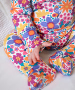 A close up of a baby wearing the GOTS organic cotton Frugi easy dressing printed baby in white/retro floral design available at Babipur.