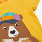 Frugi 100% organic cotton yellow short sleeve t-shirt laid flat showing a playful brown bear eating a sandwich patch on the front