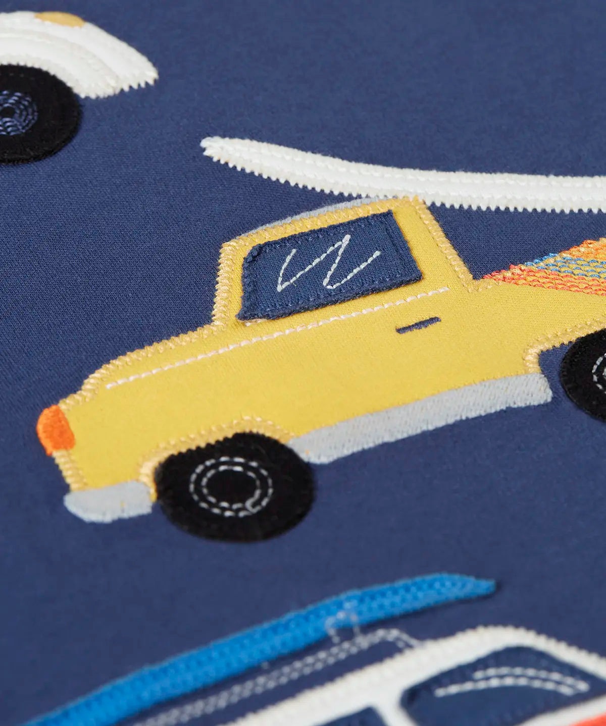 Close up of a yellow vehicle patch on the Frugi 100% organic cotton navy short sleeve t-shirt 