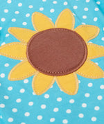 Close up of Frugi 100% organic cotton Dora playsuit in blue with white dots showing sunflower patch detail