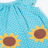 Frugi 100% organic cotton Dora playsuit in blue with white dots laid flat showing the sunflower patches on the front and elasticated neck line