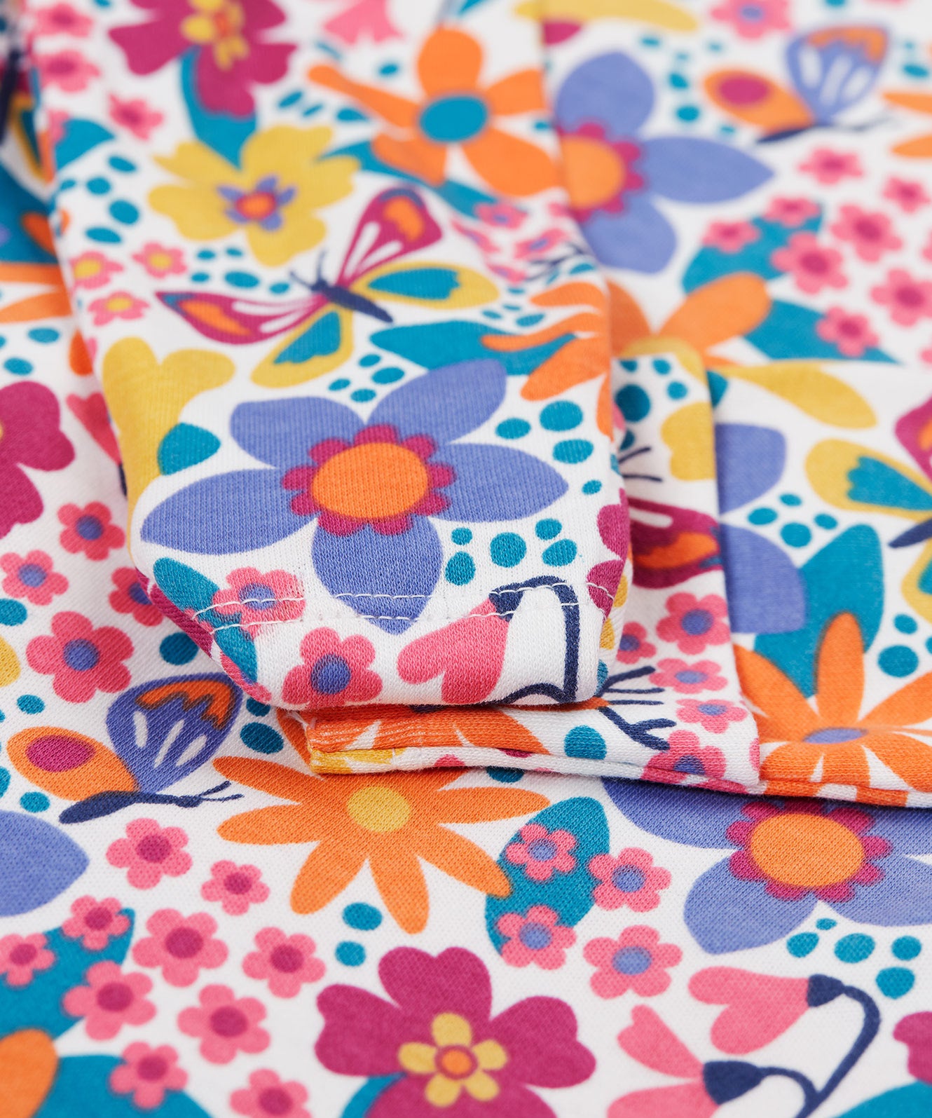 A close up of the cuff detail on the Frugi easy dressing printed babygrow in white/retro floral design available at Babipur. 