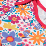 A close up of the pink trim detail on the neck and shoulder on the Frugi easy dressing printed babygrow in white/retro floral design available at Babipur.
