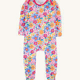 Frugi easy dressing printed babygrow in white/retro floral design available at Babipur. A GOTS organic cotton all in one with a bright retro floral design and pink trim around the neck and shoulder.