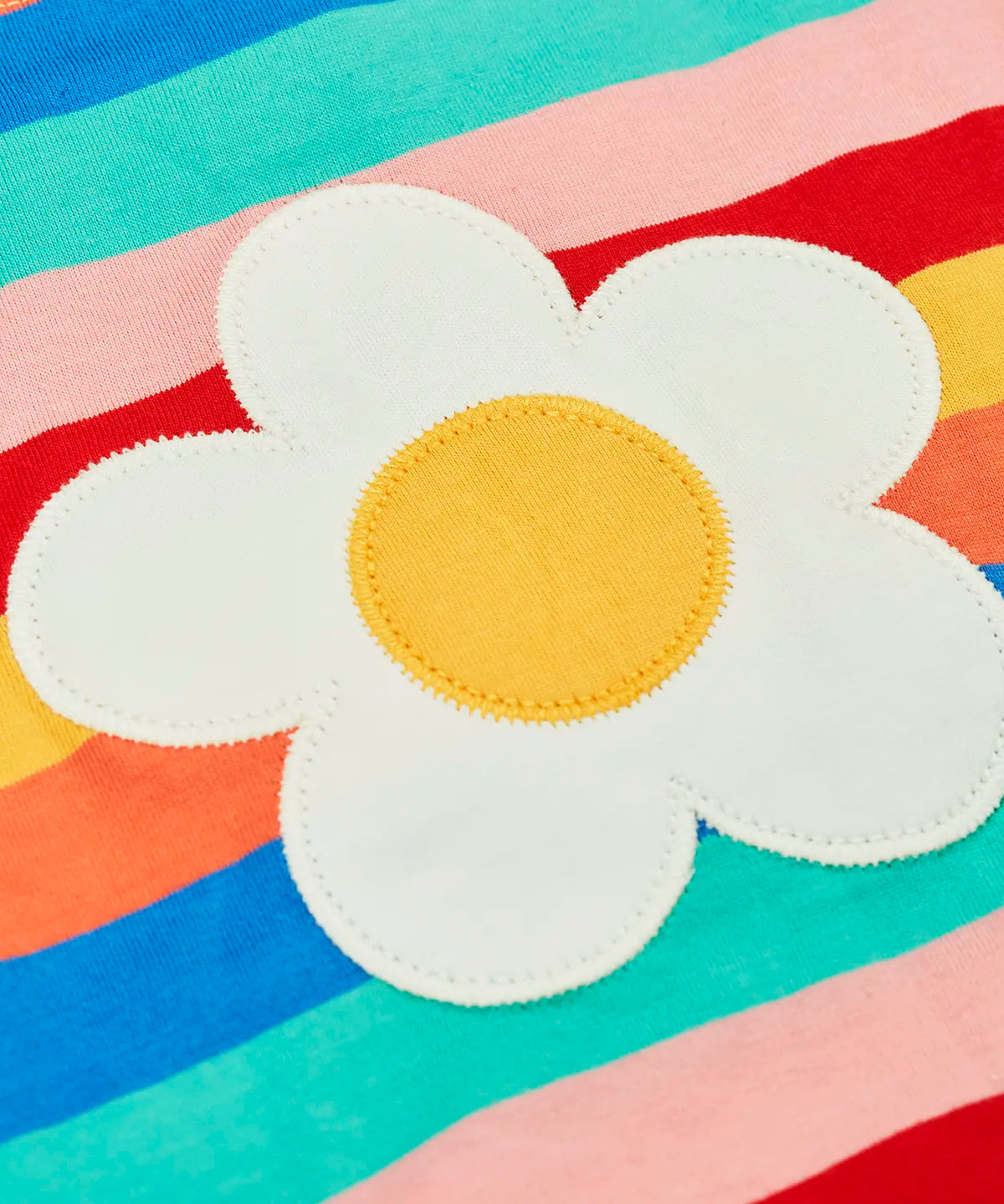 Close up of the white daisy patch on the Frugi 100% organic cotton short sleeve Fiona t-shirt in rainbow stripes 