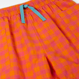Close up of the Frugi 100% organic cotton Kai shorts showing the orange and pink check and blue waist tie detail