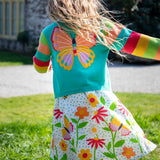 Child wearing Frugi cammie cardigan in light blue with rainbow striped sleeves showing large butterfly design on the back