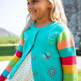 Child wearing Frugi 100% organic cotton cammie cardigan in light blue with rainbow striped sleeves showing spring embroideries on the front