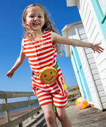 Child wearing Frugi 100% organic cotton Harlyn towelling playsuit in red and white stripes on a wooden surface