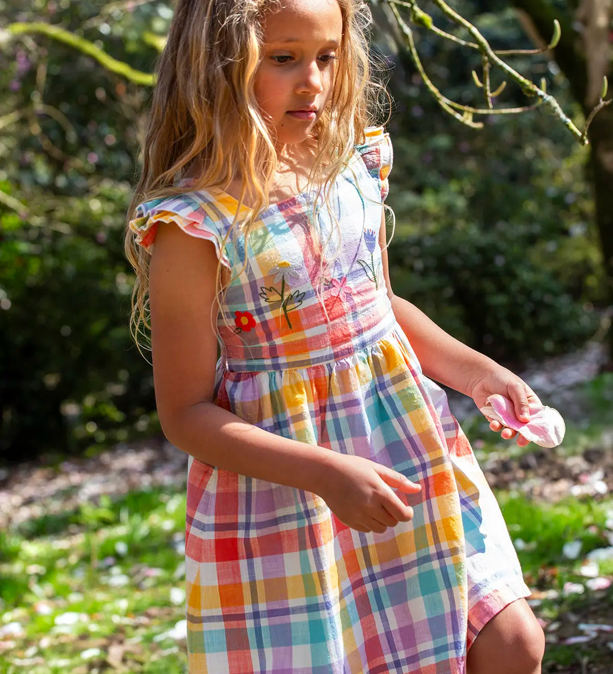Child wearing Frugi springtime dress in pastel check with hyacinth embroideries on the upper body and frilled shoulders