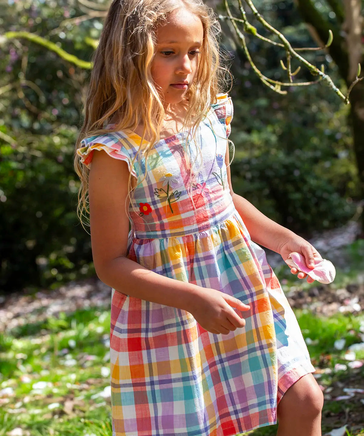 Child wearing Frugi springtime dress in pastel check with hyacinth embroideries on the upper body and frilled shoulders