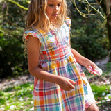 Child wearing Frugi springtime dress in pastel check with hyacinth embroideries on the upper body and frilled shoulders