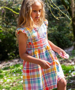 Child wearing Frugi springtime dress in pastel check with hyacinth embroideries on the upper body and frilled shoulders