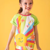 Child wearing Frugi 100% organic cotton light green raglan short sleeve t-shirt with a large happy sun print on the front against a orange background.