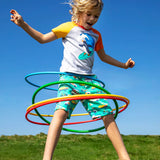 Child wearing Frugi 100% organic cotton shorts in light green with repeating beach theme vehicles. Child jumping in the air 