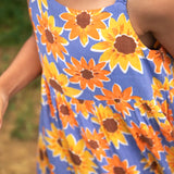 Close up of child wearing Frugi 100% organic cotton Sophie summer sleeveless dress in purple with a repeating sunflower print