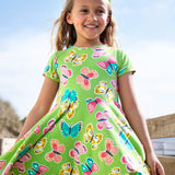 Child wearing Frugi 100% organic cotton spring skater dress in green with a repeating colourful butterfly print.