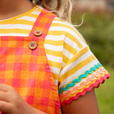 Close up of Child wearing Frugi 100% organic cotton yellow and white striped t-shirt showing the ric rac decorative trim 