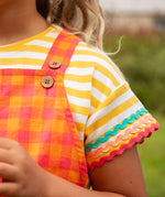 Close up of Child wearing Frugi 100% organic cotton yellow and white striped t-shirt showing the ric rac decorative trim 