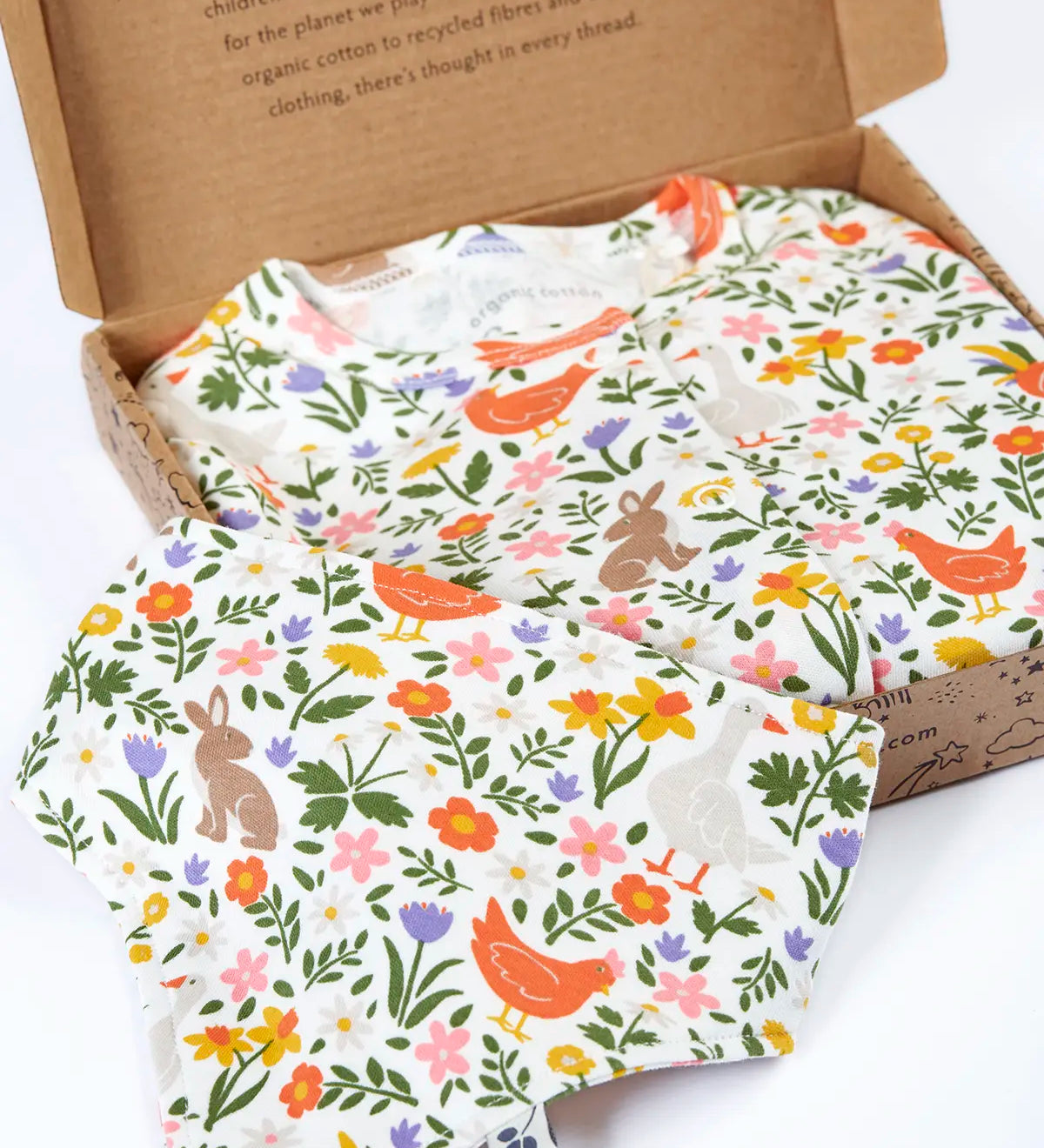 Frugi 100% organic cotton white babygrow with repeating meadow inspired design and a matching bib presented in a decorated box