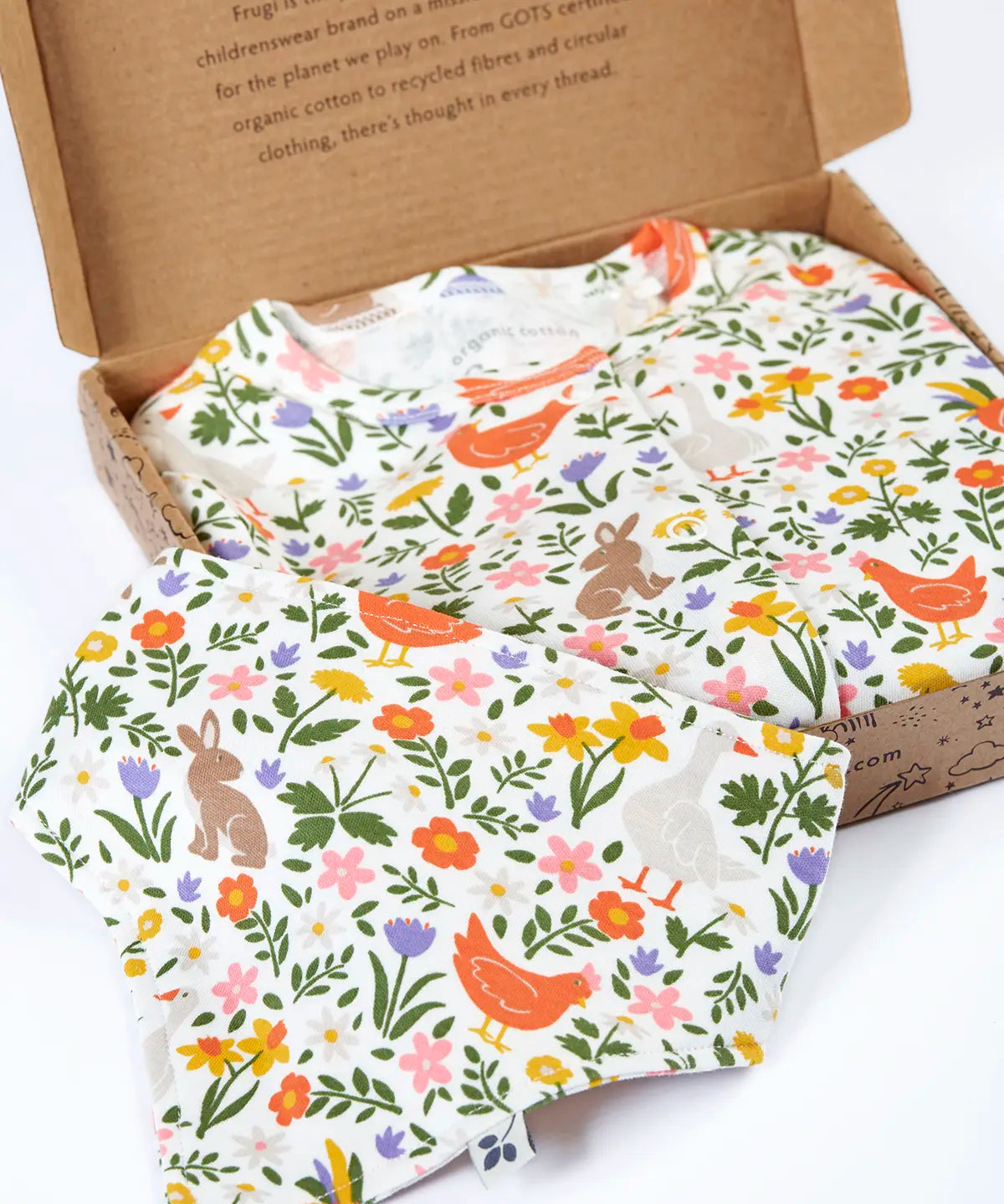 Frugi 100% organic cotton white babygrow with repeating meadow inspired design and a matching bib presented in a decorated box