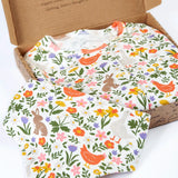Frugi 100% organic cotton white babygrow with repeating meadow inspired design and a matching bib presented in a decorated box