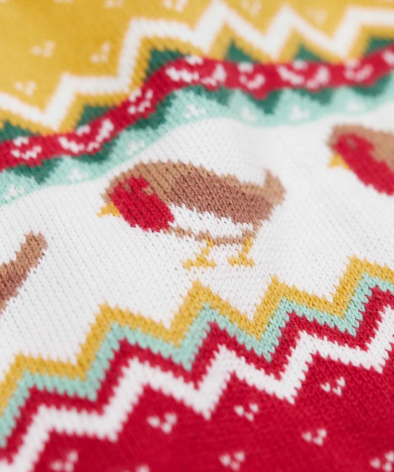 A close up of the robin on the Frugi lumi knitted festive romper fair isle available at Babipur. A GOTS organic cotton soft knitted all in one in a fairisle design with robins. Features button fasteners running down from the shoulder.