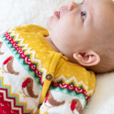 A baby wearing the Frugi lumi knitted festive romper fair isle available at Babipur. A GOTS organic cotton soft knitted all in one in a fairisle design with robins. Features button fasteners running down from the shoulder.