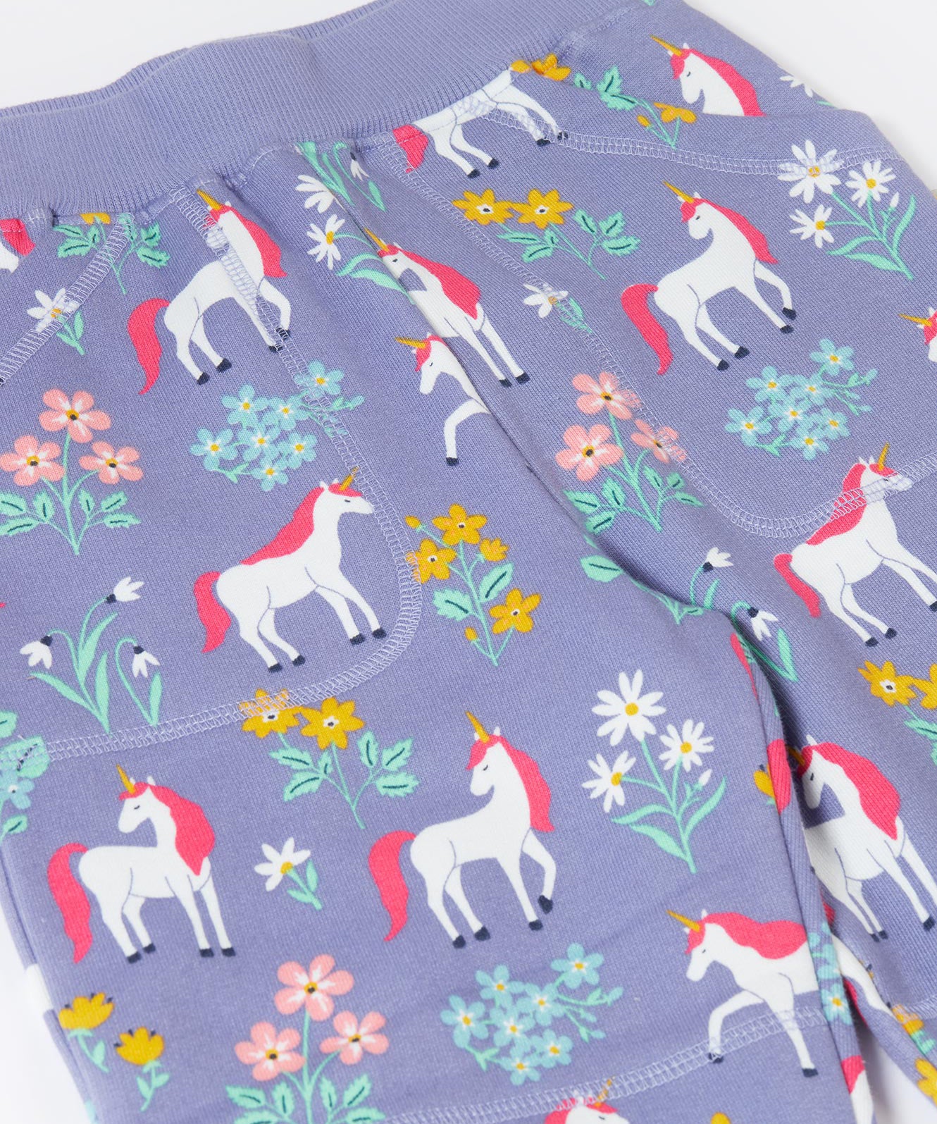 A close up of the pockets and the waistband on the Frugi malpas joggers in unicorn / floral available at Babipur. A GOTS organic cotton jogger in light purple with a playful unicorn and floral design. Features elasticated cuffs and side pockets