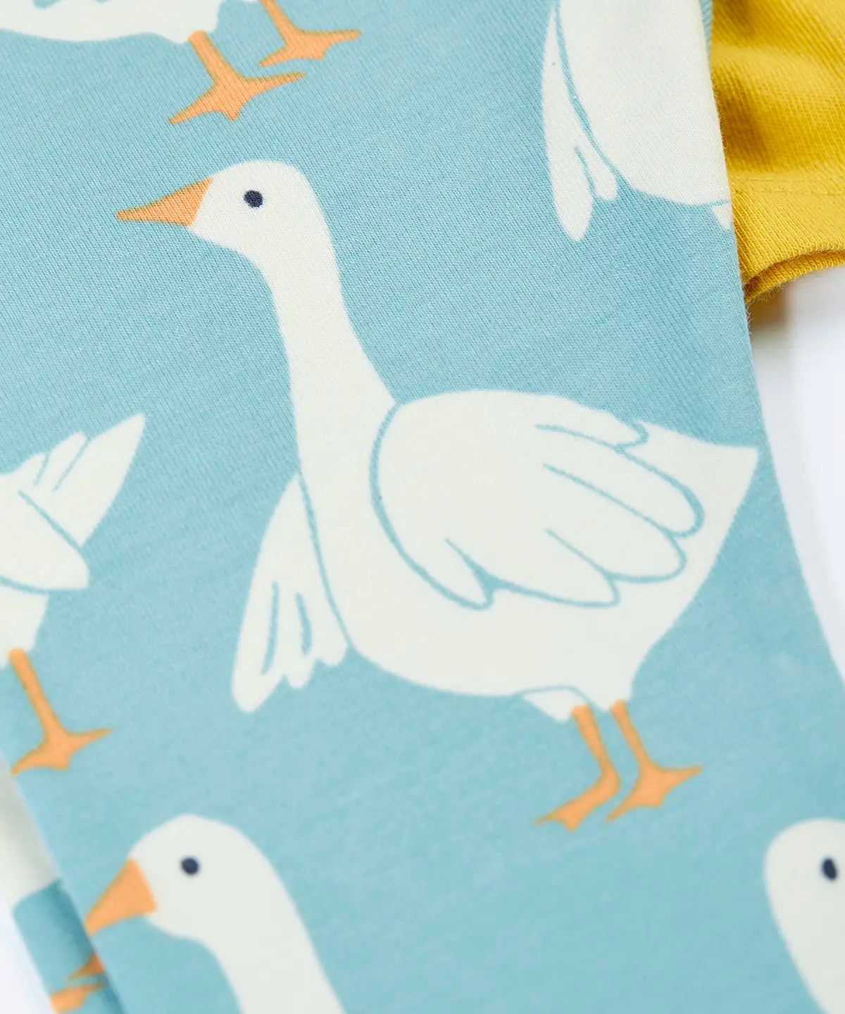 Close up of the light blue leggings from the Frugi bumblebee goose gaggle outfit showing the repeating goose print