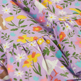 Close up of Frugi 100% organic cotton skater dress in violet purple showing the repeating meadow inspired print