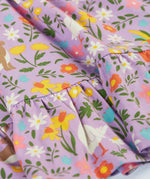 Close up of Frugi 100% organic cotton skater dress in violet purple showing the repeating meadow inspired print