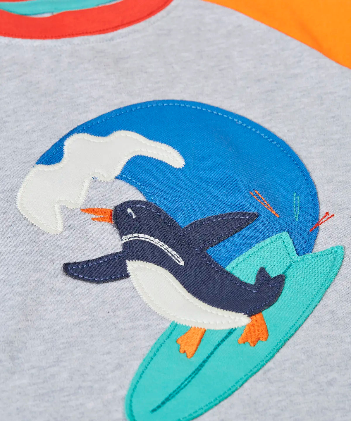 Close up of the Frugi 100% organic cotton short sleeve t-shirt in grey  Showing a surfing penguin patch on the front