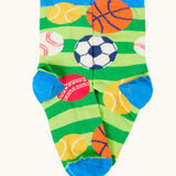 Frugi 100% organic cotton sock in green stripes with different repeating sport balls designs. Showing blue heel and toe panel