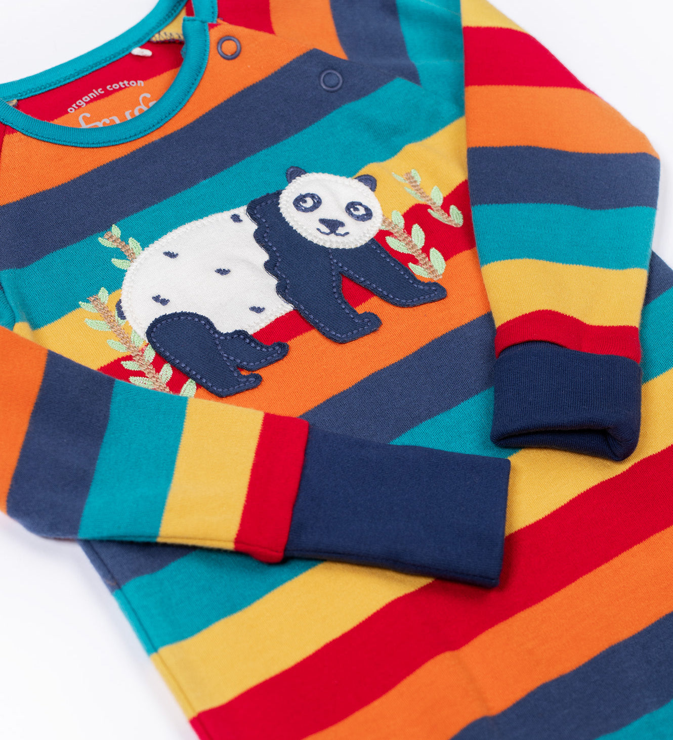 A close up of the panda applique on the front of the Frugi rowan romper in big rainbow stripe / panda available at Babipur. A GOTS organic cotton all in one in a bright rainbow inspired striped design with  a playful applique on the front. Features a popper fastener on the shoulder.