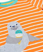 Frugi 100% organic cotton short sleeve t-shirt in orange and white stripes laid flat showing  a seal patch on the front 