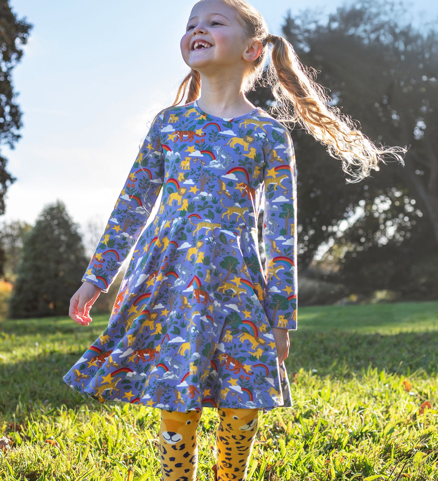 A child wearing the Frugi sofia skater dress in grape purple with a into the wild print with cheetah tights. Available at Babipur. A GOTS organic cotton lilac skater dress with a playful wildlife print. 