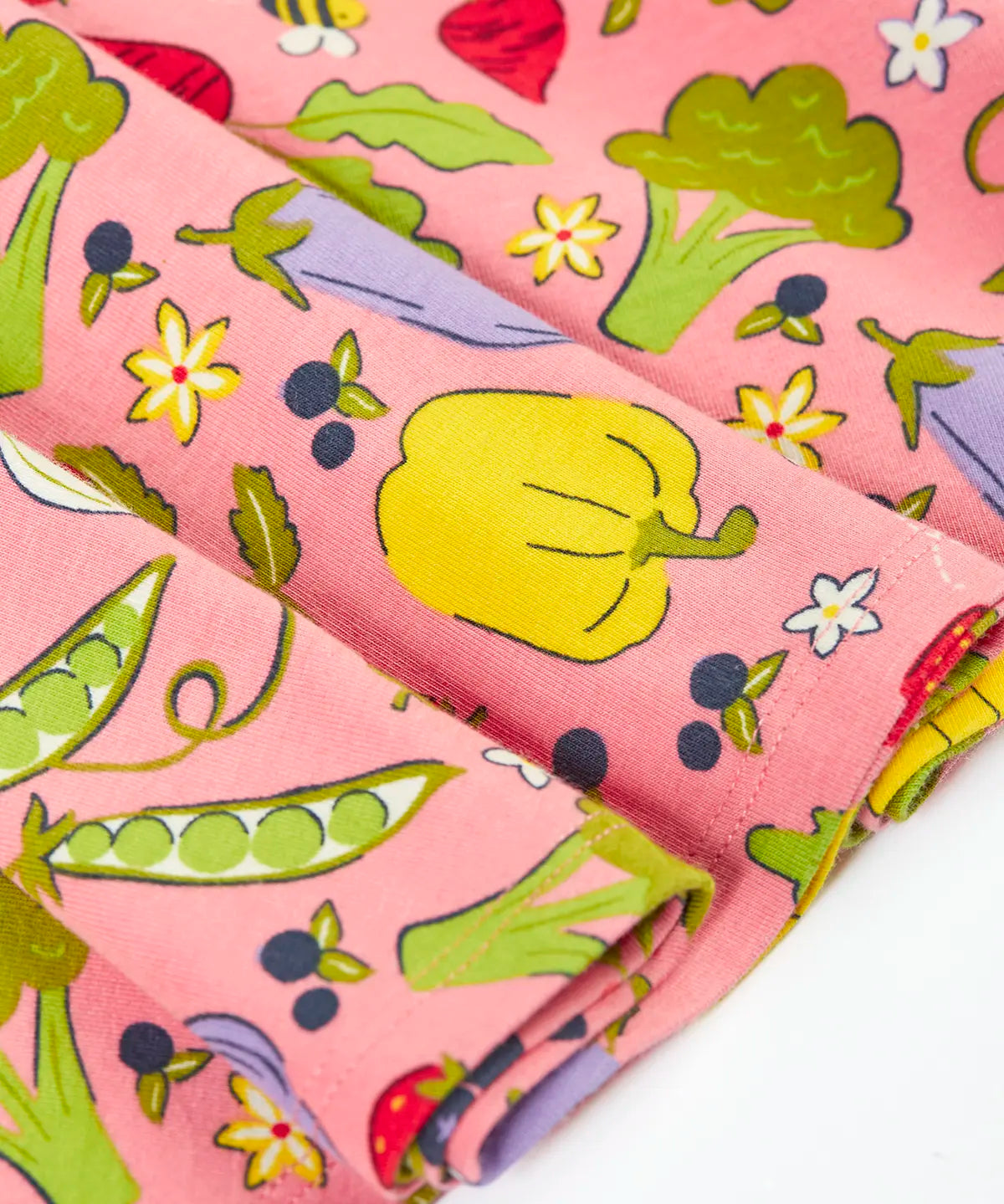 Close up of Frugi's 100% organic cotton spring skater dress in pink showing the repeating fruit and veg print