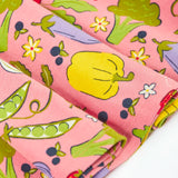 Close up of Frugi's 100% organic cotton spring skater dress in pink showing the repeating fruit and veg print