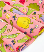 Close up of Frugi's 100% organic cotton spring skater dress in pink showing the repeating fruit and veg print