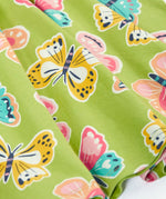Close up of the Frugi 100% organic cotton spring skater dress in green showing the repeating colourful butterfly print.