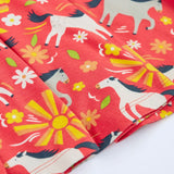 Close up of the repeating prints of white and grey horses on the Frugi 100% spring skater dress in coral pink