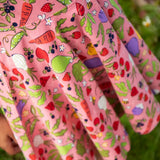Close up of child wearing Frugi's 100% organic cotton spring skater dress in pink showing repeating fruit and veg print 