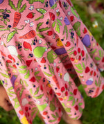 Close up of child wearing Frugi's 100% organic cotton spring skater dress in pink showing repeating fruit and veg print 
