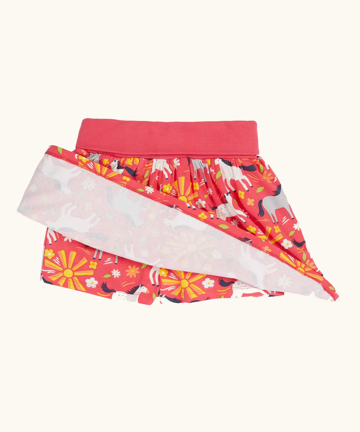 Frugi spring skort in coral pink with a repeating white and grey pony print showing the shorts underneath