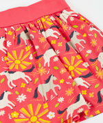 Frugi  spring skort in coral pink laid flat showing the repeating white and grey pony and sunshine print.