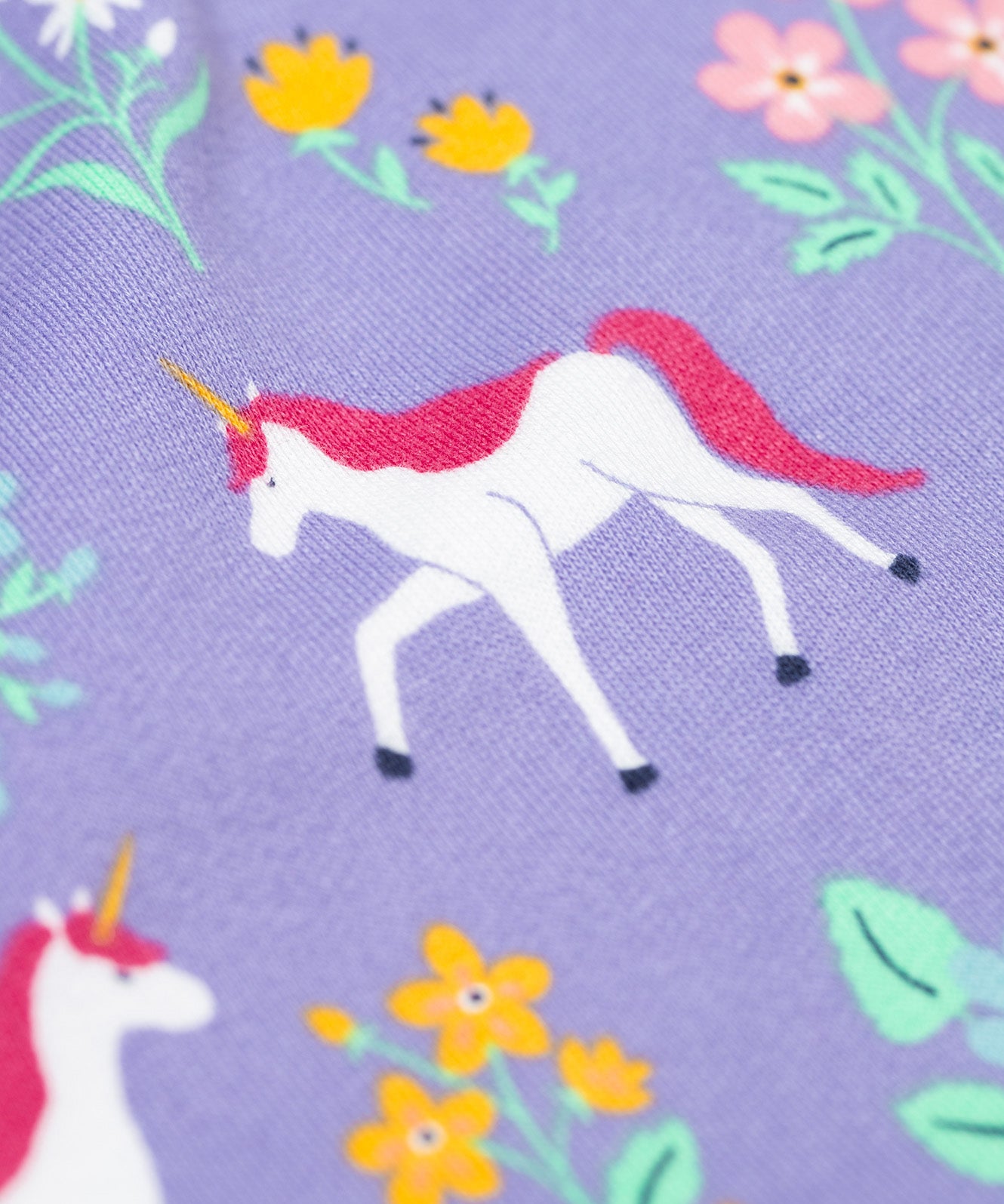 A close up of the unicorn featured on the print on the Frugi superb sweatshirt in unicorn floral available at Babipur. A soft GOTS organic cotton sweatshirt in lilac with a unicorn and floral print all over.