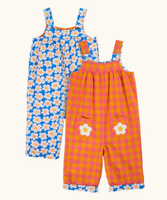 Frugi 100% organic cotton Sylvie reversible dungarees showing a blue with repeating daisy design and a orange and pink check design on reverse side
