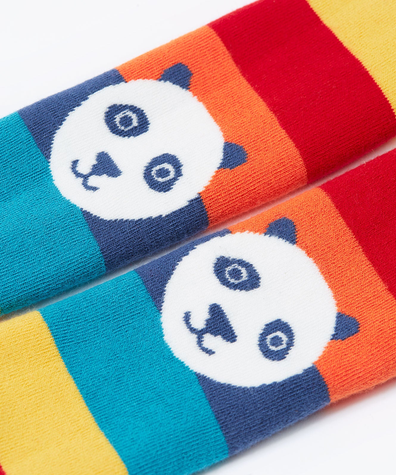 A close up of the pandas on the knees of the Frugi toasty tights in big rainbow stripes/panda available at Babipur. A GOTS organic cotton tights with bright and bold rainbow stripes with a panda design on the knees.